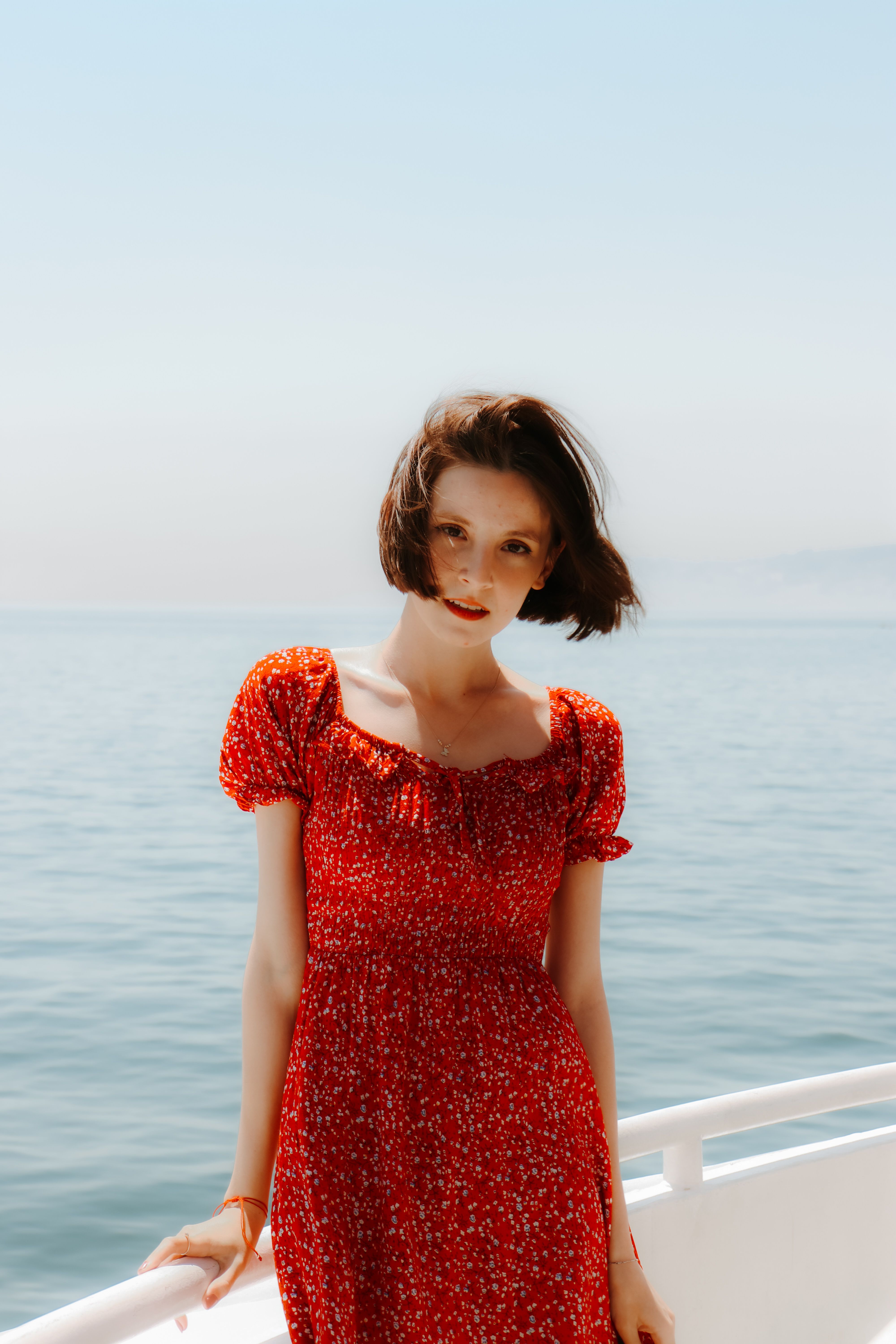 Woman in Red Floral Dress Standing on White Boat · Free Stock Photo