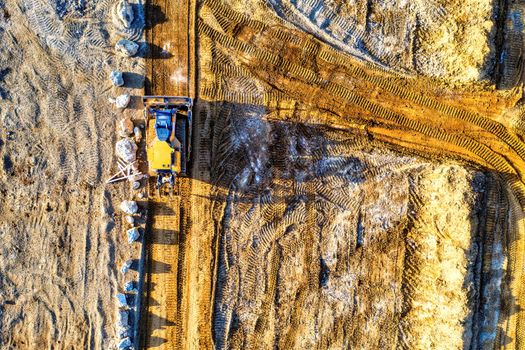 Top-down view of a bulldozer moving sand and rocks at a construction site in Rochester, MN.