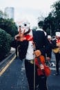 People in White Mask Playing Musical Instruments