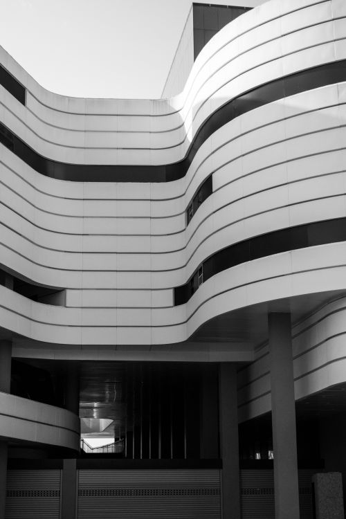 Free A striking modern building facade featuring sleek, futuristic curves and geometric patterns. Stock Photo