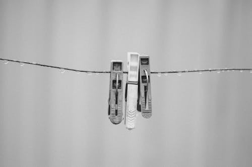 Grayscale Photo of Clothespins on Wet Wire