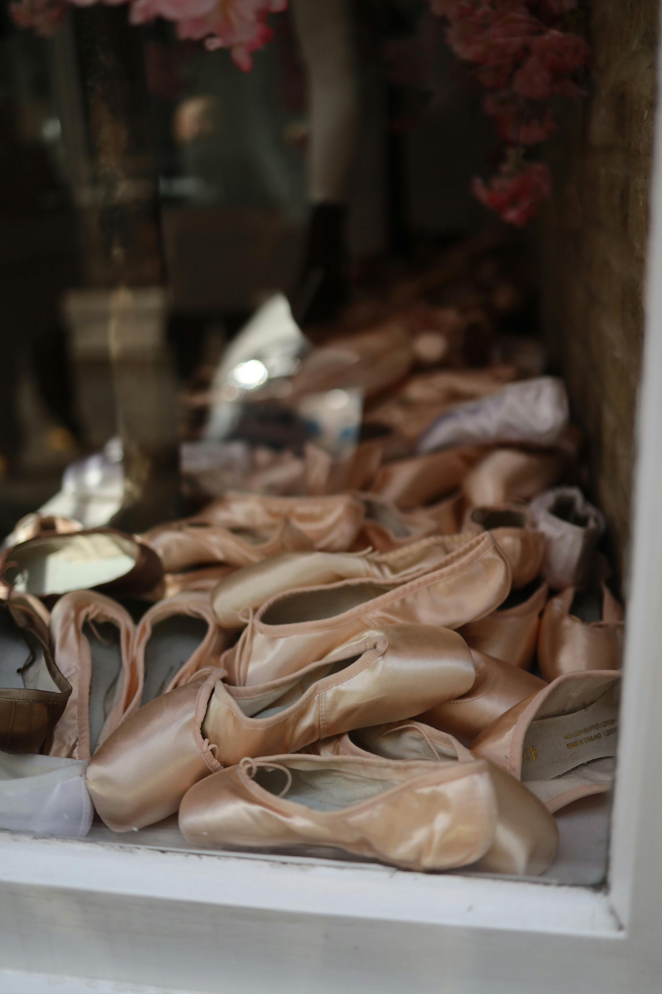 Free Close-up of ballet pointe shoes elegantly displayed in a storefront window. Stock Photo