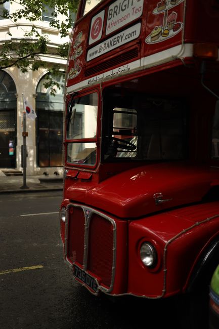 Iconic red double-decker bus parked on a rainy city street, showing vintage charm.