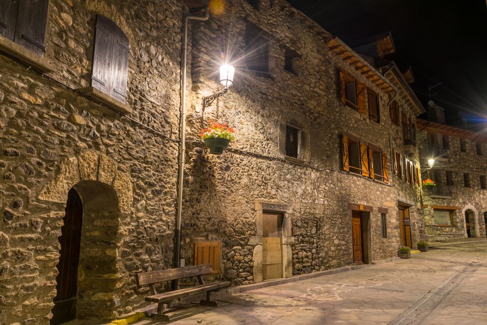 Warm outdoor lamp glowing against a stone wall at night
