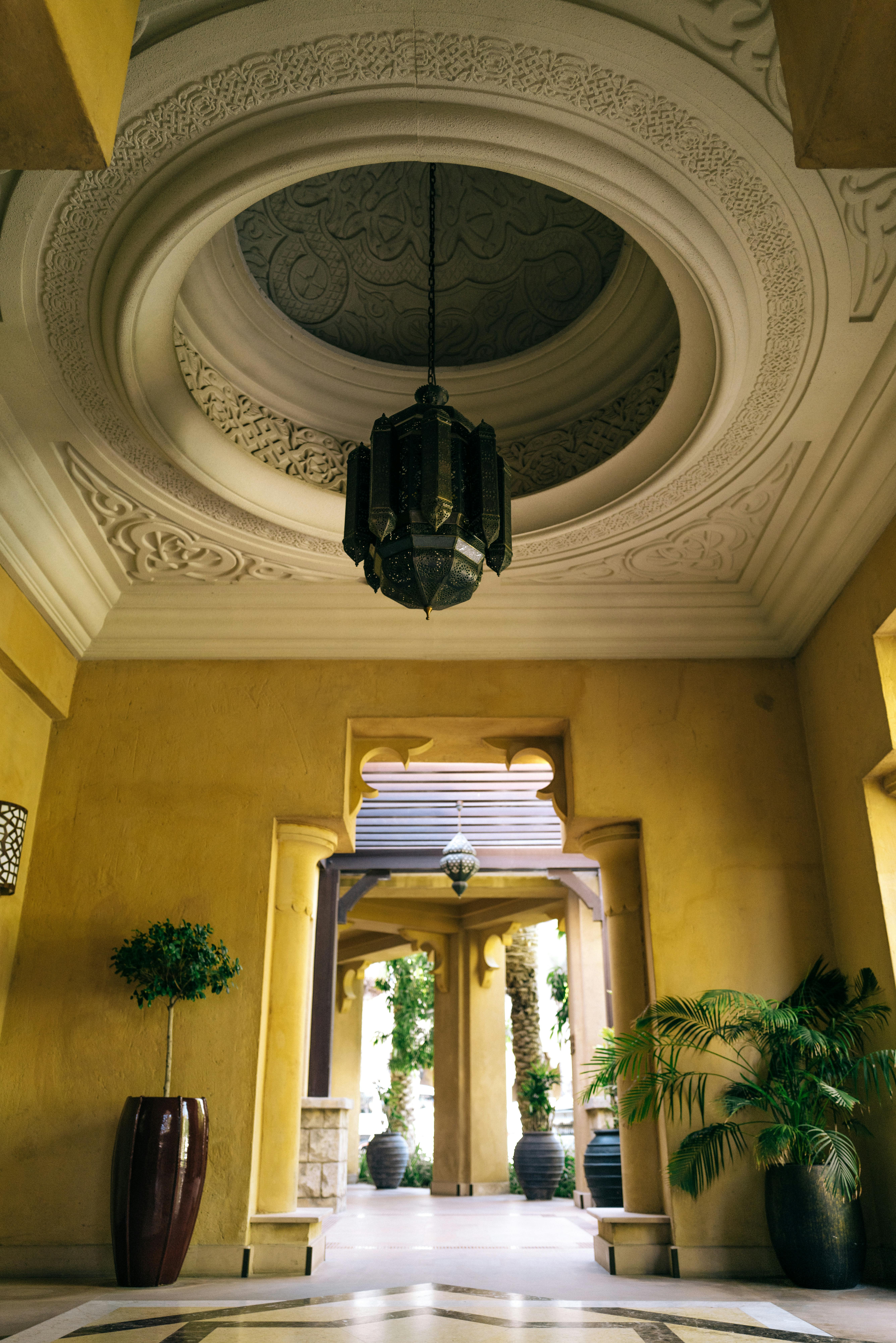 Luxurious interior courtyard featuring intricate ceiling, chandelier, and greenery.