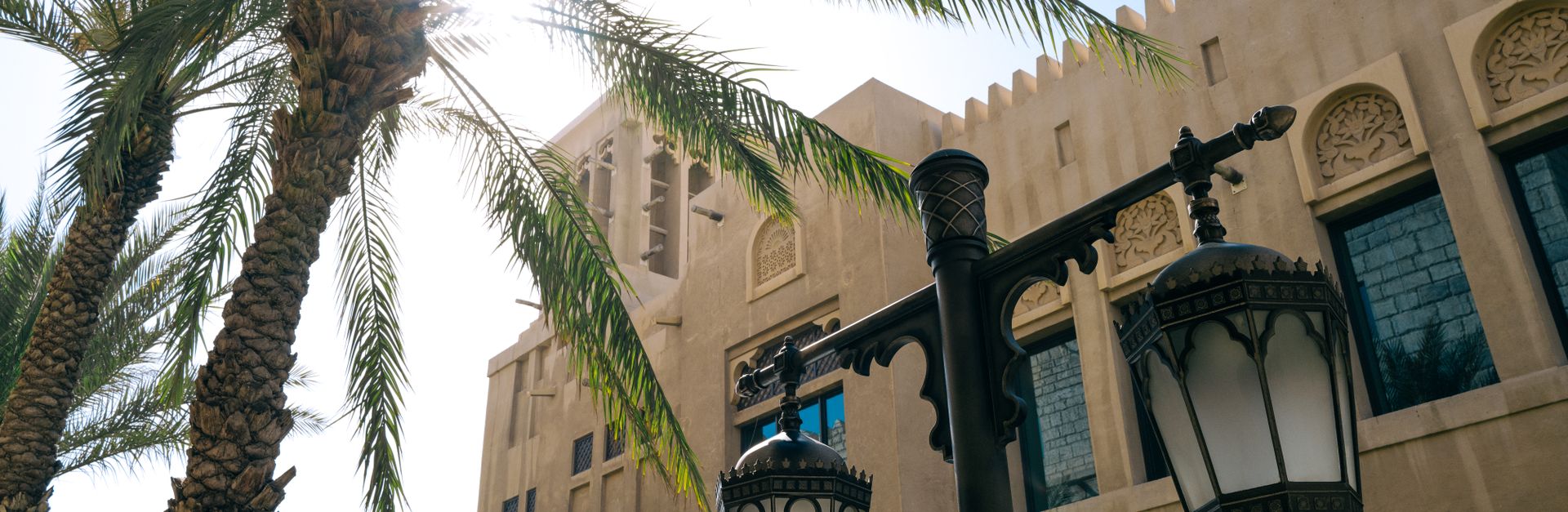 Sunlit view of Middle Eastern architecture and palm trees, offering a blend of tradition and nature.