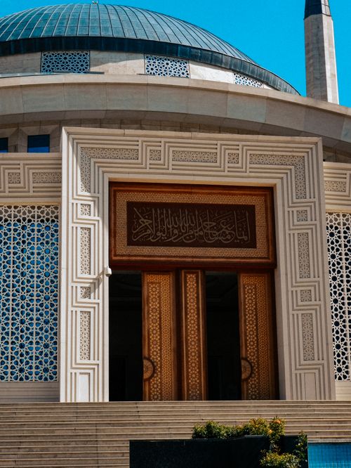 Free A beautifully ornate mosque entrance featuring an Ottoman style design with intricate patterns and Arabic script. Stock Photo