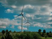 Wind Turbine on Green Grass Field Under Blue and White Cloudy Sky