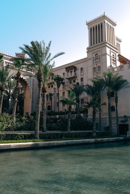 Beautiful Arabian-style resort architecture with palm trees and water canal in Dubai.