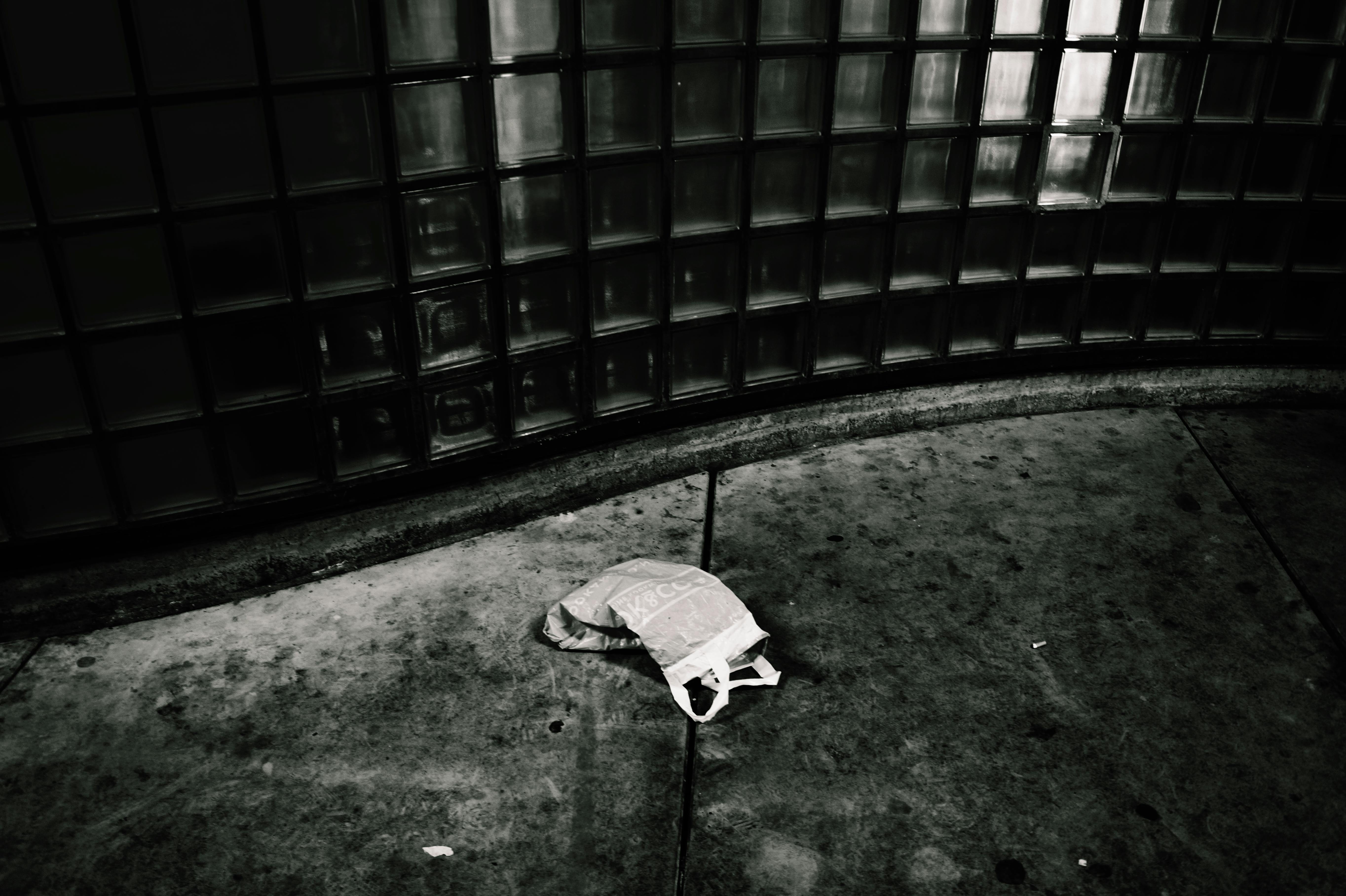 一张单色图像捕捉了城市衰败，人行道上有一个废弃的塑料袋