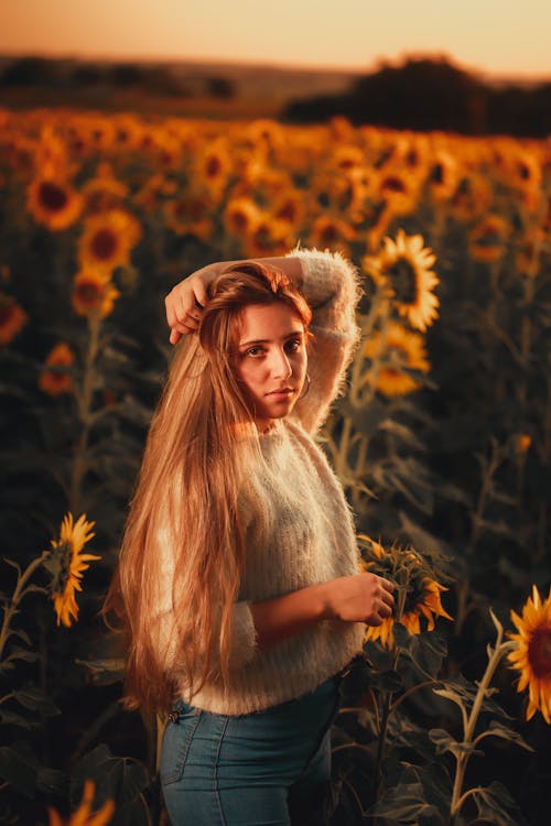 Beautiful Woman with Long Hair standing on a Sunflower Field