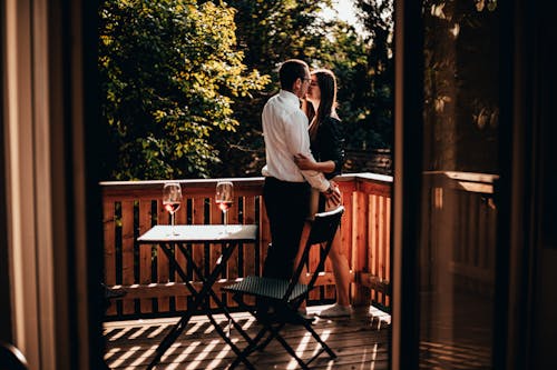 Photo of a Couple Kissing on a Balcony