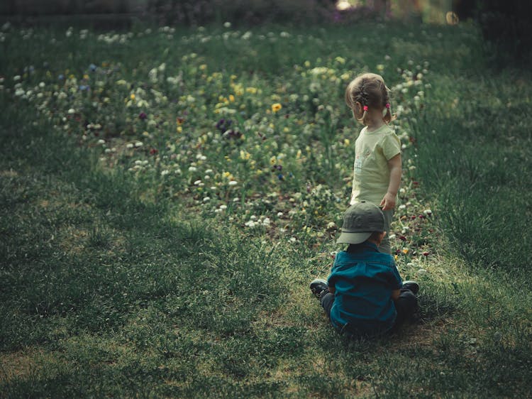 Girl And A Boy On Grass Field With Flowers