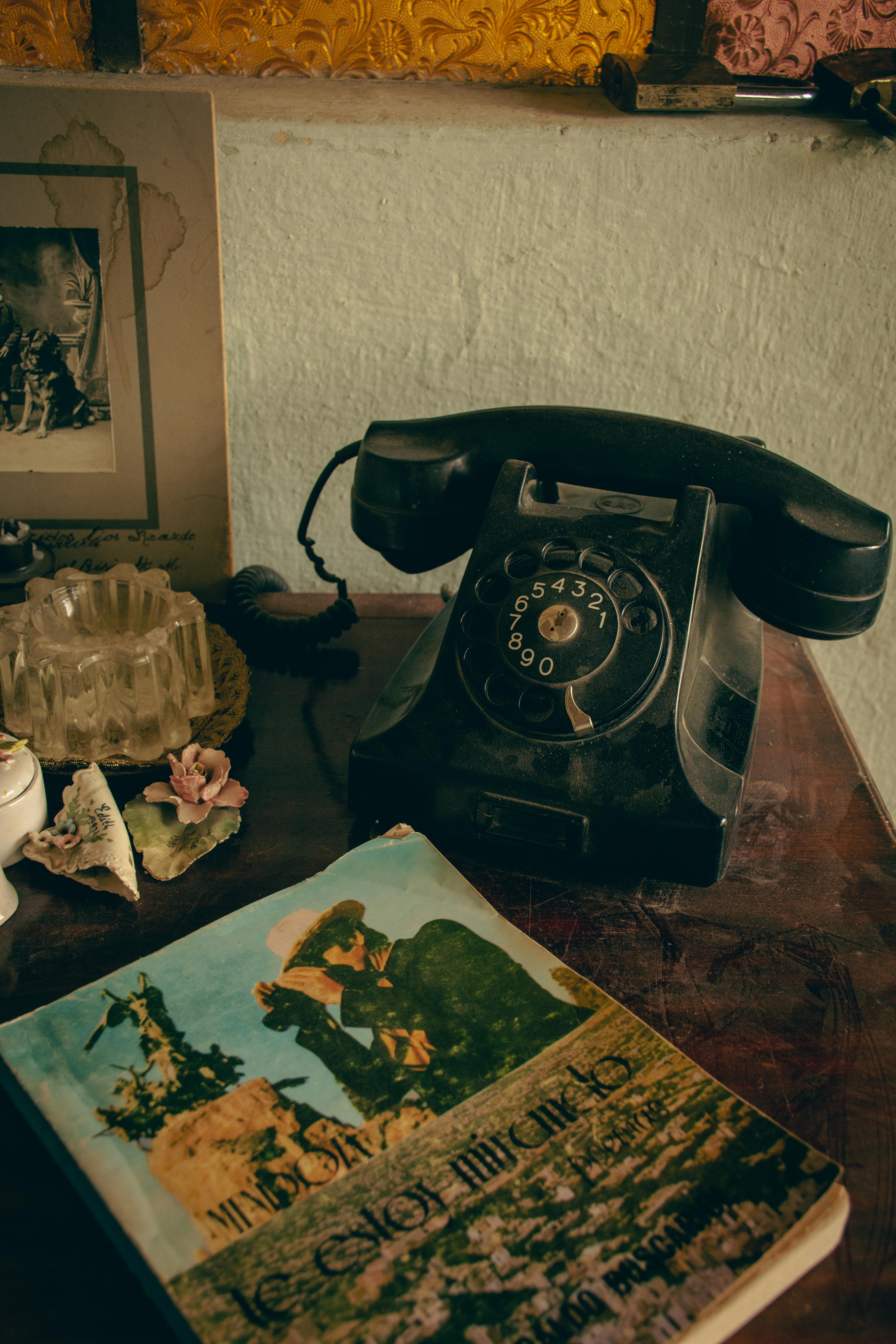 A classic rotary phone and vintage book on an antique wooden desk.