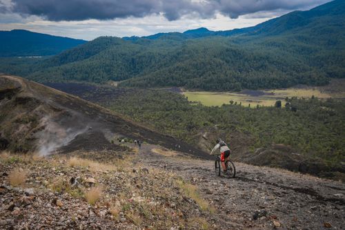 Free A cyclist rides down a rugged mountain trail in Michoacán, México, surrounded by lush green forests. Stock Photo