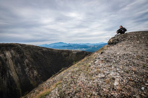 Free A Woman in Black Clothes Sitting on the Mountain Stock Photo