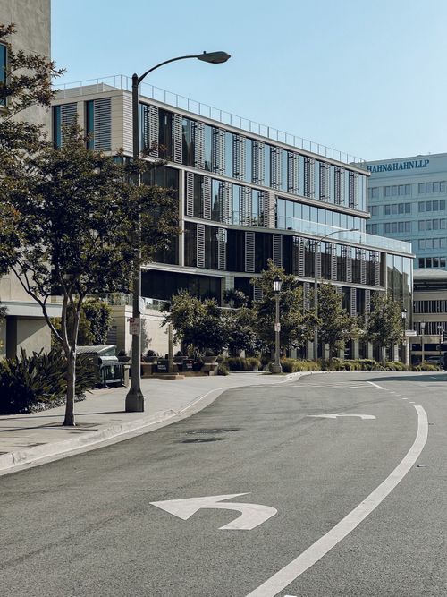 Free Street view of modern buildings with glass facades and greenery on a sunny day. Stock Photo