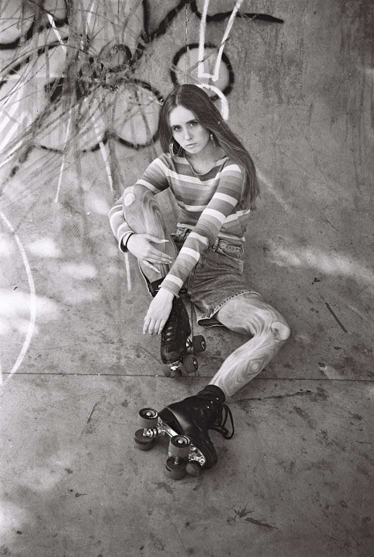 Black And White Picture Of A Woman Sitting On Concrete Ramp In Rollerskates