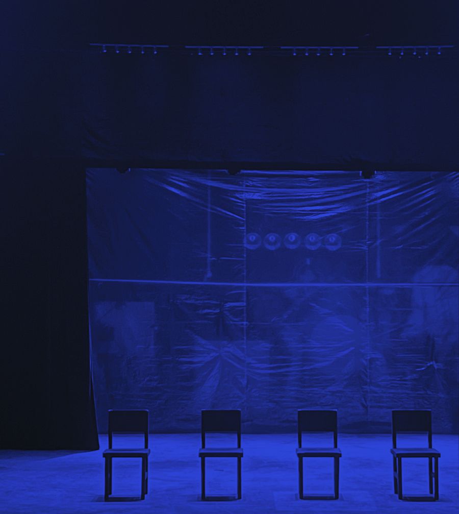 An evenly lit blue cyclorama on a dark stage