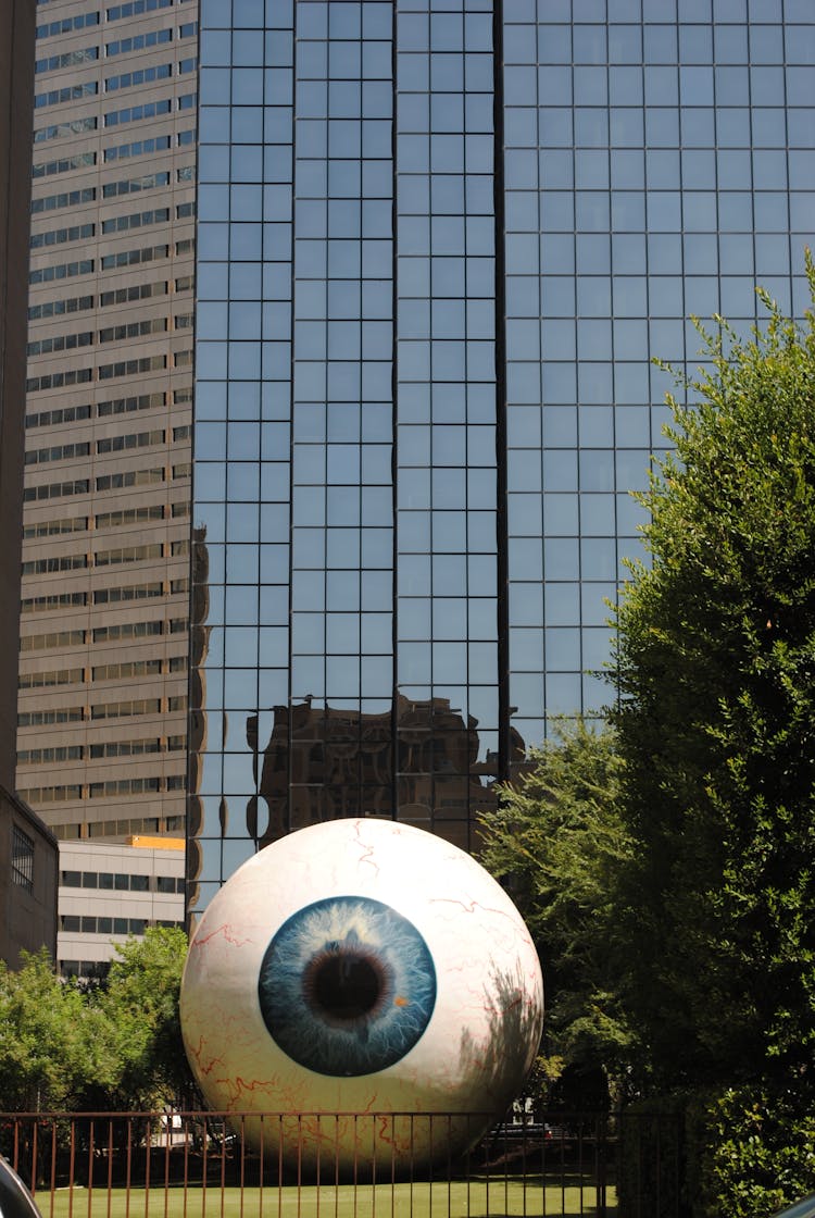 Modern Eye Sculpture Near Glass Skyscraper