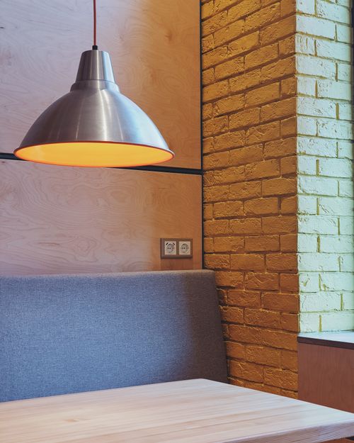 Free Stylish interior featuring a wooden table, brick wall, and pendant lamp, exuding a minimalist vibe. Stock Photo