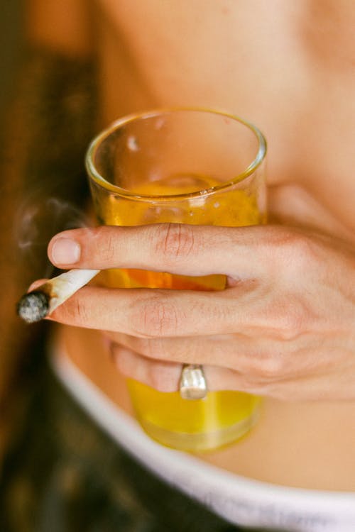 Free Hand Holding a Drink and a Lit Cigarette Stock Photo