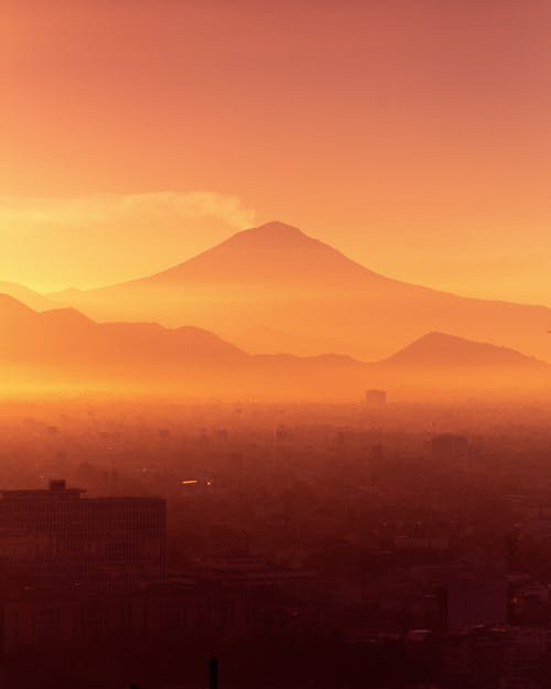 Free Volcano Behind a City Hidden in Fog Stock Photo