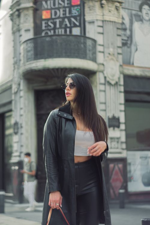 Free A fashionable woman poses confidently in front of an iconic building in Mexico City. Stock Photo