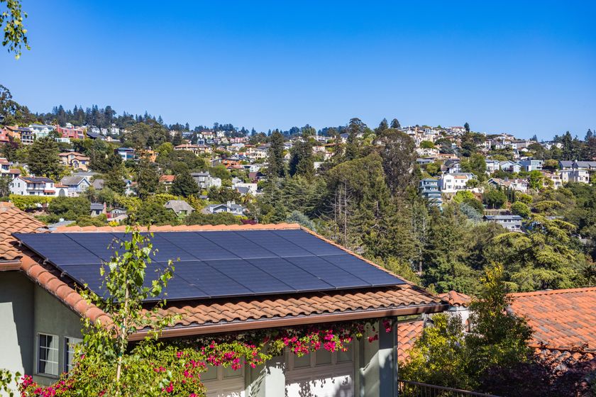 Solar array on a tiled home roof above a wooded hillside — photo by Robert So on Pexels