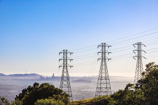 Electrical pylons with city skyline and bay view on a clear day.