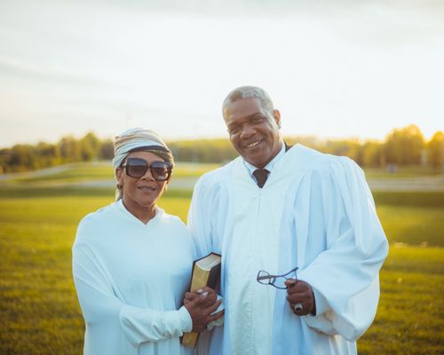 Free A happy couple of ministers in white robes enjoying a sunny outdoor setting, embodying spirituality and joy. Stock Photo