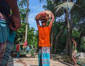 Man in Orange Crew Neck T-shirt and Brown Hat Standing on Wooden Dock