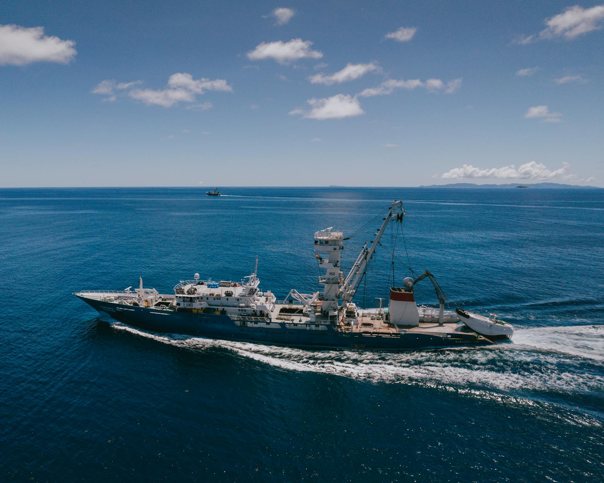A ship cruising across the vast ocean under a bright blue sky near Seychelles.