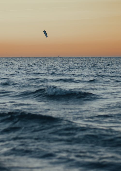 Person Kite Surfing on Sea during Sunset