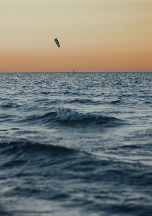 Free Silhouette of a kite surfer at sunset on the sea off Rostock beach, Germany. Waves create dynamic motion. Stock Photo