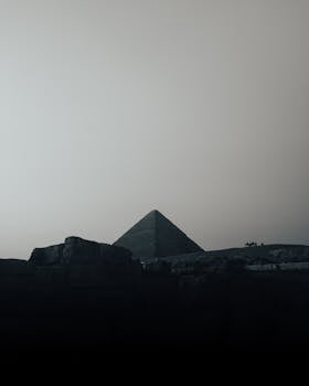 Moody silhouette of the Great Pyramid of Giza captured under a dim sky, exuding mystery and ancient allure.