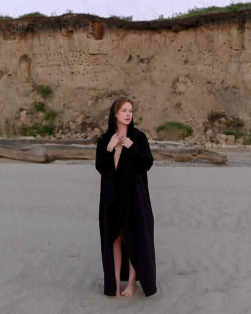 Woman in Black Long Sleeve Dress Standing on White Sand