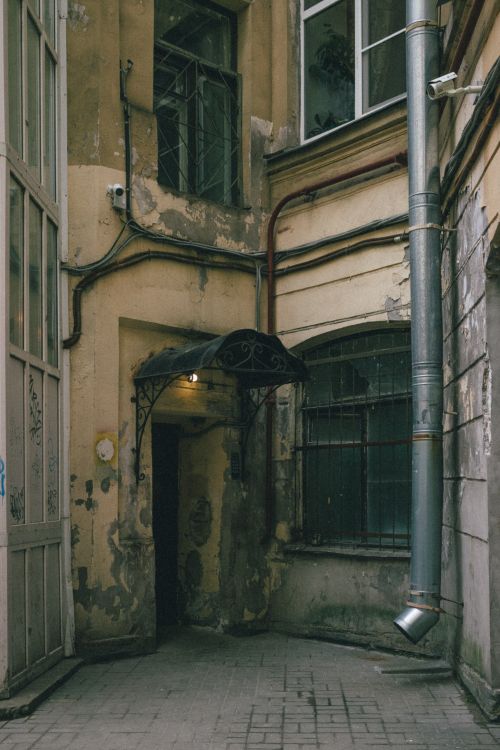 Free A moody shot of an aged building corner with worn walls and a dimly lit entrance. Stock Photo
