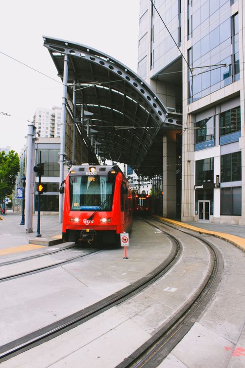 Free Red train arrives at a modern San Diego station, highlighting urban transportation. Stock Photo