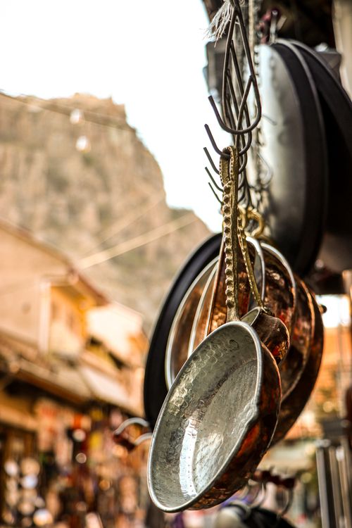 Free Copper pots and pans hanging in a vibrant Turkish market with mountain backdrop. Stock Photo