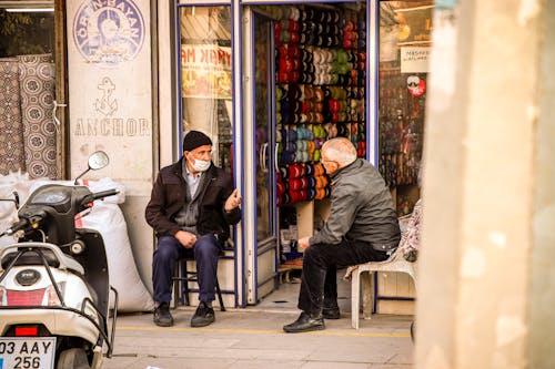 Elderly People Standing Outside a Commercial Establishment while Having a Conversation