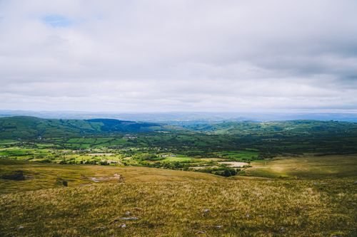Free Captivating aerial view of lush green fields in the Welsh countryside with a cloudy sky above. Stock Photo