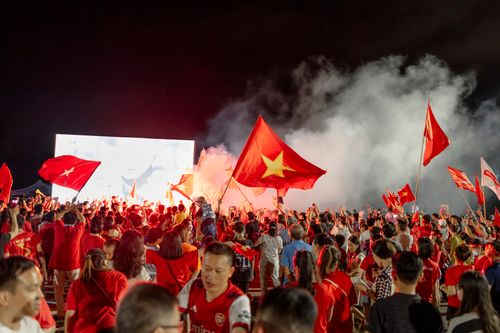 Free A vibrant crowd waves red Vietnamese flags at an outdoor nighttime event. Stock Photo