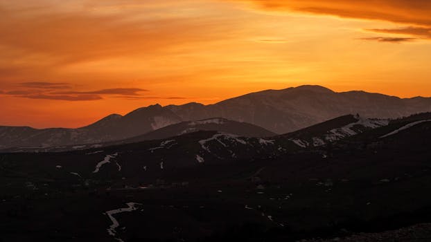 Stunning sunset over snow-capped mountains in Iran, showcasing vivid golden hour colors.