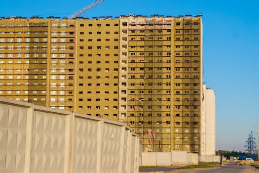 A tall modern high-rise building under construction against a clear blue sky.