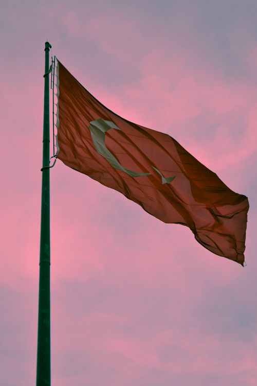 Free Turkish flag waving against a vibrant pink sky, symbolizing national pride and unity. Stock Photo