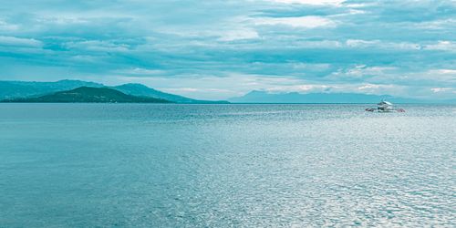 Free Peaceful seascape in Moalboal with a lone boat on the ocean and a scenic horizon. Stock Photo