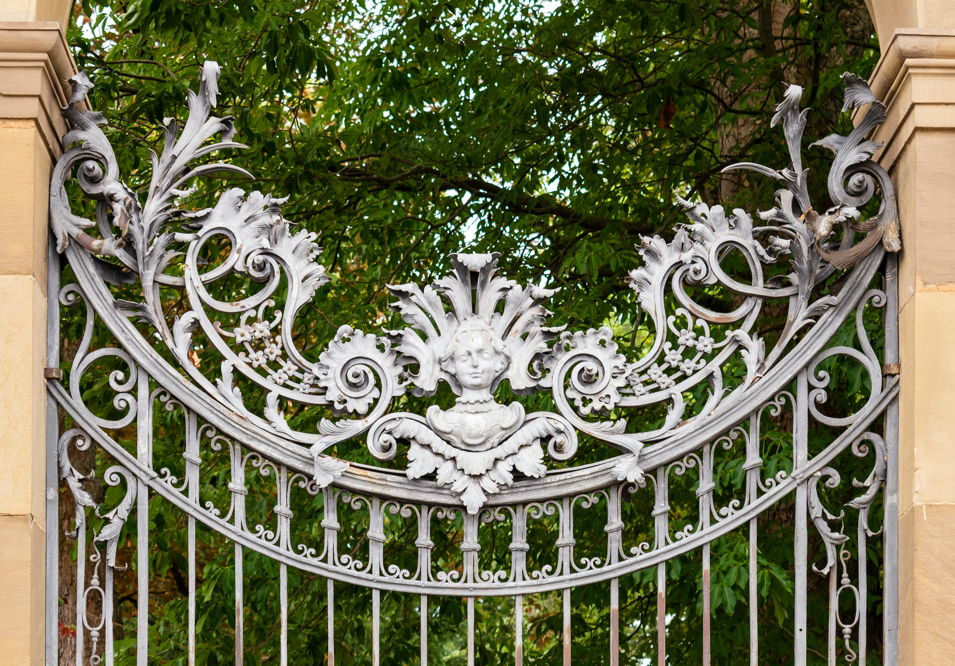 The silver ornamental gate with foliage decor and angels head, made out of metal, entrance to the Court Garden of Bavarian Residence in Würzburg