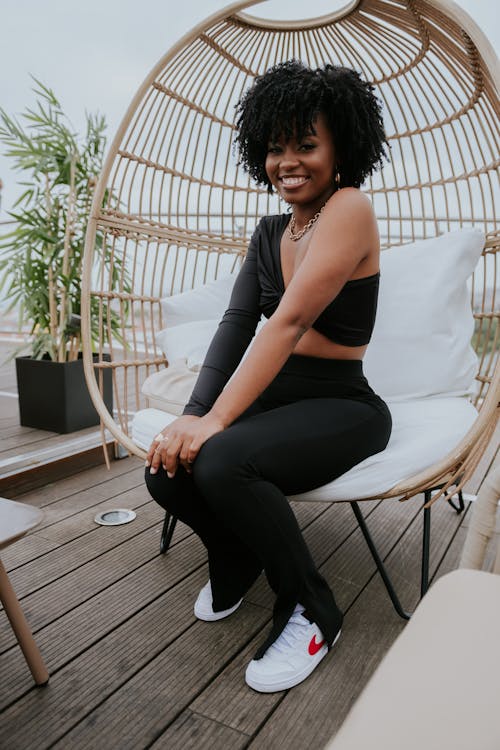 A Woman in Black Pants Sitting on a Wooden Chair