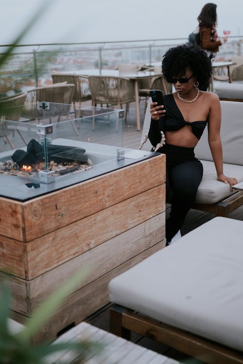 Woman in Black Brassiere and Black Pants Sitting on White Table